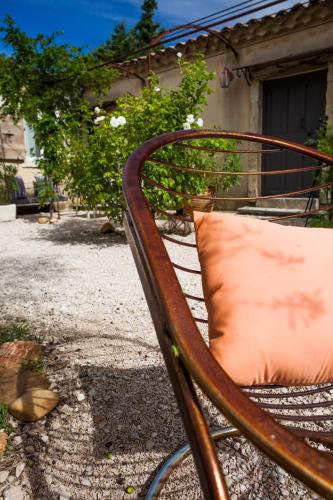 a rusty bench with an orange pillow on it at Apres La Sieste in Saint-Laurent-des-Arbres
