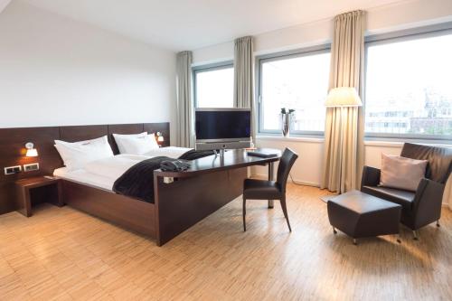 Schlafzimmer mit einem Bett, einem Schreibtisch und einem Stuhl in der Unterkunft Altera Hotel in Oldenburg