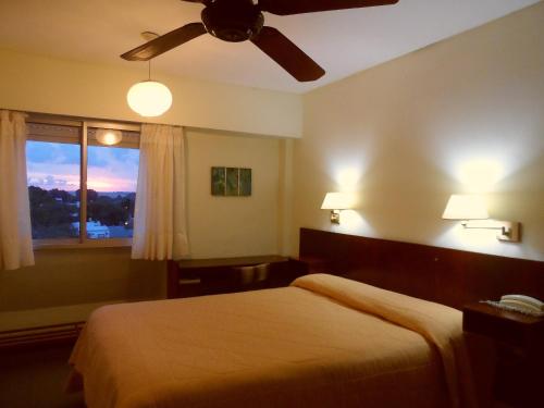 a bedroom with a bed with a ceiling fan and a window at Hotel Eo Park in San Clemente del Tuyú