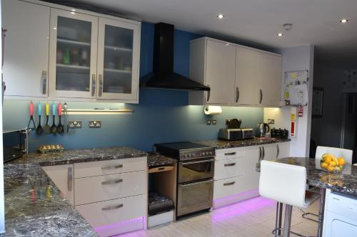 cocina con armarios blancos y paredes azules en Taunton House en Great Yarmouth