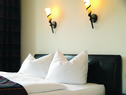 a bed with white pillows and two lights on the wall at Traumparadies in Bad Sulza