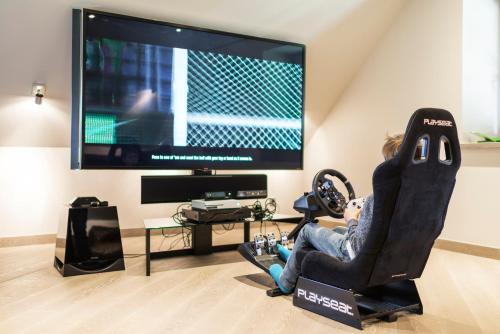 a person sitting in a gaming chair in front of a tv at Sala Resort Plateliai & SPA in Plateliai