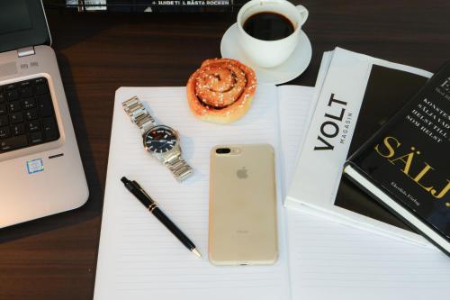 a desk with a phone and a cup of coffee and a pastry at Best Western Plus Park Airport Hotel in Arlanda
