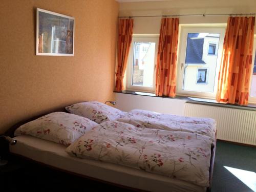 a bed in a bedroom with two windows at Pension Graef in Cochem