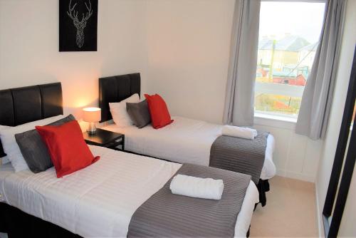 a hotel room with two beds and a window at Kelpies Serviced Apartments MacGregor- 2 Bedrooms in Grangemouth