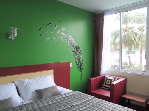 a bedroom with a green wall with a bed and a window at Your Place Inn Surin in Surin