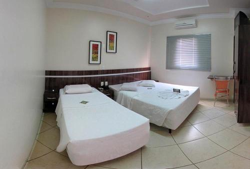 a room with two beds and a table in it at Dourados Center Hotel in Dourados