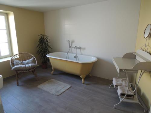 ein Badezimmer mit einer Badewanne, einem Stuhl und einem Tisch in der Unterkunft La Quincaillerie in Audierne