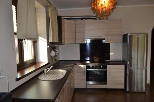 a kitchen with wooden cabinets and a stainless steel refrigerator at Villa Sole in Pruszcz Gdański
