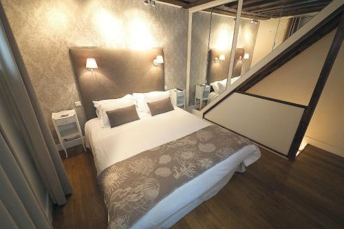 ein Hotelzimmer mit einem Bett und einem Spiegel in der Unterkunft Louvre Parisian ChicSuites in Paris