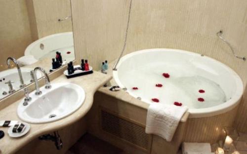 baño con bañera y lavabo con corazones rojos. en Ros Tower Hotel en Rosario