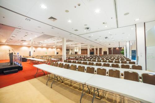 an empty lecture hall with white tables and chairs at Premier Kraków Hotel in Kraków