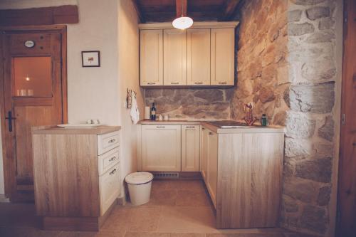 a kitchen with wooden cabinets and a stone wall at Villa DELUXE in Gabonjin