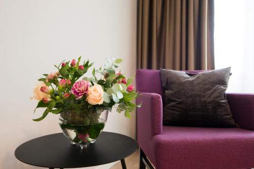 a vase of flowers on a table next to a purple chair at Best Western Plus Park Airport Hotel in Arlanda