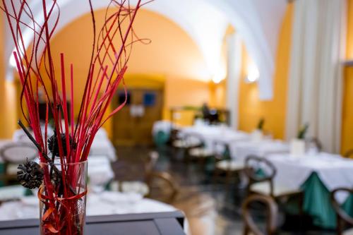 a vase with red branches in a room with tables at Hotel Conventual de Alcántara in Alcántara