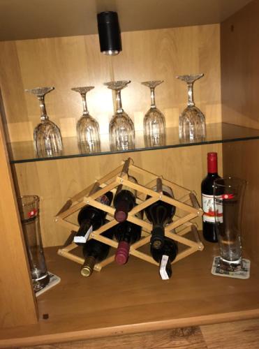 a shelf with wine glasses and wine bottles at FeWo s Runde Wiese RW in Greifswald
