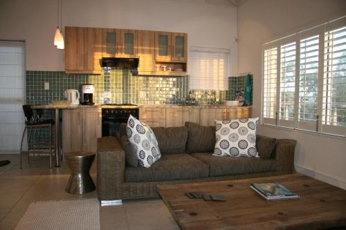a living room with a couch and a kitchen at Freshhh in Bloubergstrand