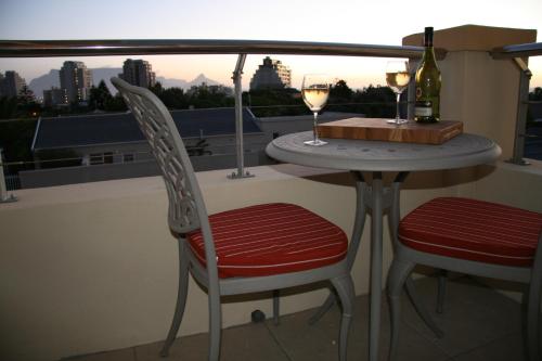 a table with two chairs and two glasses of wine at Freshhh in Bloubergstrand