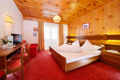 a hotel room with a bed and a desk at Hotel Alpenblick in Pfelders