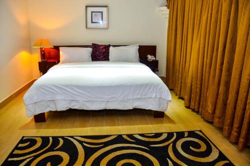 a bedroom with a large white bed and a rug at The Cape Hotel in Monrovia