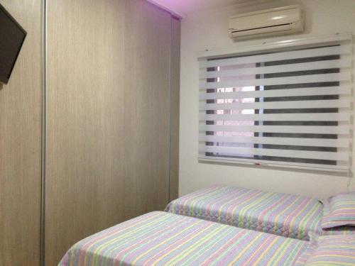 um quarto com uma cama e uma janela em Flat Guaruja Diferenciado no Guarujá