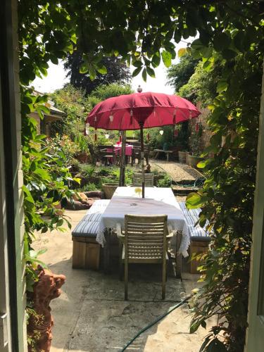 a table with a red umbrella in a garden at Ellesmere House in Castle Cary