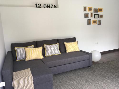 a gray couch with yellow pillows in a living room at 12Onze in Espinho