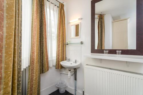 a bathroom with a sink and a mirror at Earls Court Hotel in London