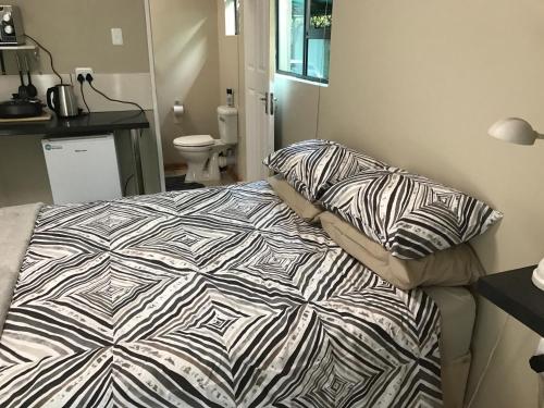 ein Schlafzimmer mit einem Bett mit einer Bettdecke und Kissen in der Unterkunft B@home in Bloemfontein