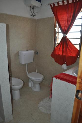 a bathroom with a toilet and a sink and a window at Coral Village in Malindi