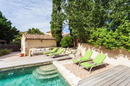 a backyard with a pool with chaise lounges and a row of chairs at Apres La Sieste in Saint-Laurent-des-Arbres
