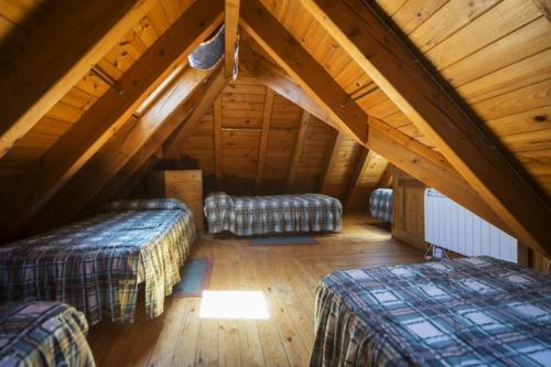 a attic room with two beds and a wooden floor at Fonda Eth Petit - Sólo adultos,niños a partir de 12 años in Escuñau