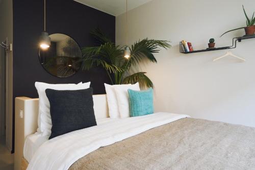 a bedroom with a bed with pillows and a mirror at Latroupe Hotel Jardin Secret in Brussels