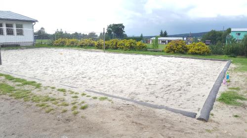 a large sandy volleyball court in front of a house at Jcamp in Nové Město pod Smrkem