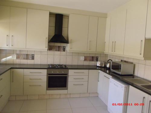 a kitchen with white cabinets and a stove top oven at Chalet no.1 Primula in Johannesburg