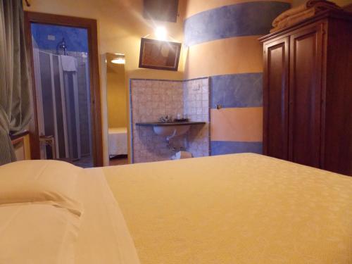 a bedroom with a bed and a bathroom with a sink at Ca' Virginia Country House Wellness in Montecalvo in Foglia