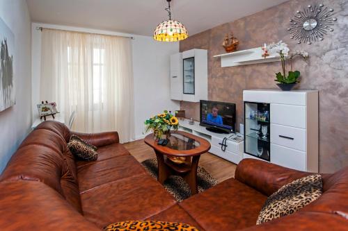 a living room with a brown leather couch and a tv at Vista mare - Sea View in Rovinj