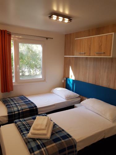 two beds in a small room with a window at Camping Taimì in Marina di Massa