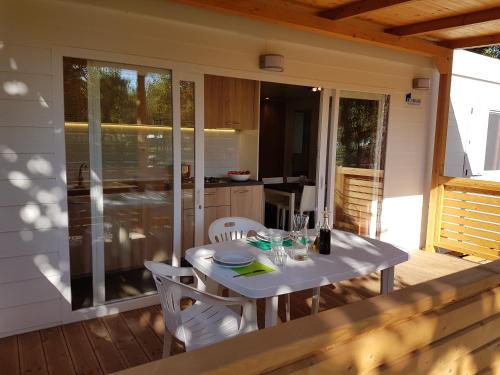 a white table and chairs on a deck with a kitchen at Camping Taimì in Marina di Massa