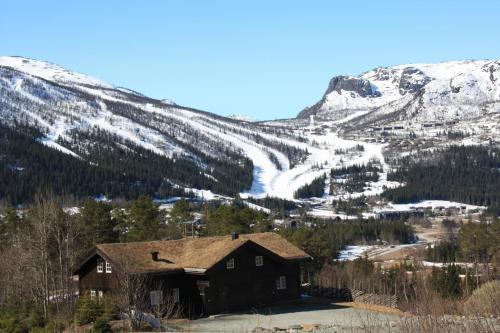 a house in front of a mountain with snow at Kirkebøen Hytter in Hemsedal
