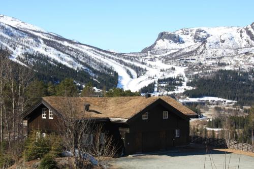 a house with a snow covered mountain in the background at Kirkebøen Hytter in Hemsedal