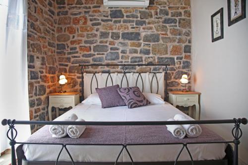 een bed in een kamer met een bakstenen muur bij Kalo Nero Apartments in Makry Gialos