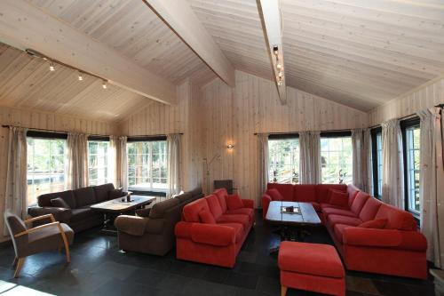 a living room with red furniture and windows at Kirkebøen Hytter in Hemsedal