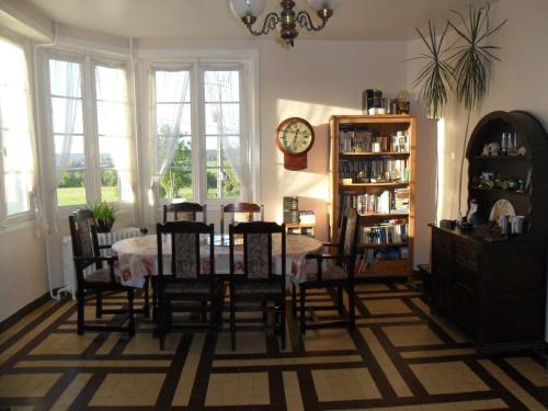 ein Esszimmer mit Tisch und Stühlen und einer Uhr in der Unterkunft Les Hautes Loignieres in Pré-en-Pail