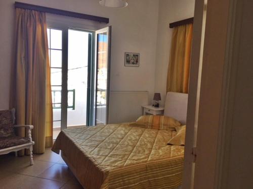- une chambre avec un lit et une porte donnant sur un balcon dans l'établissement Papanikola House 1, à Astypalée