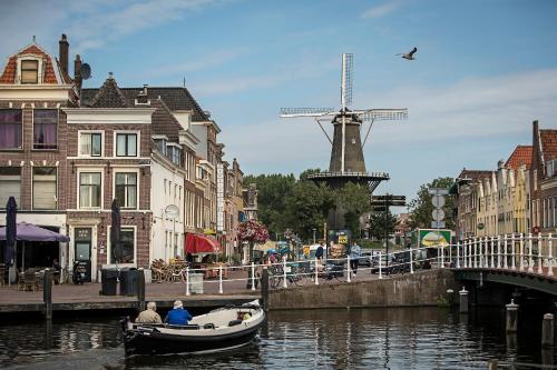 twee mensen in een boot in een kanaal met een windmolen bij City Hotel Rembrandt in Leiden