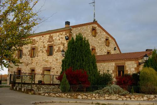 an old stone building with a tree in front of it at Bungalows Granja Escuela Arlanzón in Arlanzón