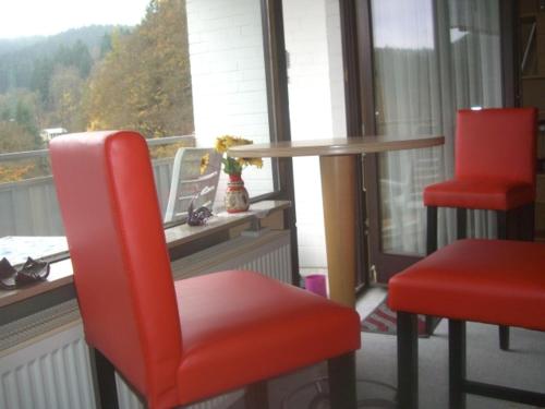 a table and two red chairs in front of a window at Ferien Penthouse Panoramablick oder Studio Panoramablick in Bad Grund