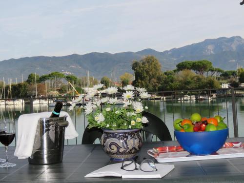 una mesa con un jarrón de flores y un tazón de fruta en Alla Foce del Magra - Villa sul fiume con posto barca vicino Cinque Terre, en Ameglia