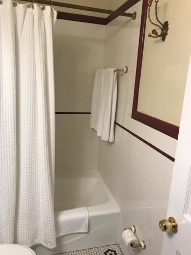a bathroom with a white shower curtain and a bath tub at Elaine's Cape May Boutique Hotel in Cape May